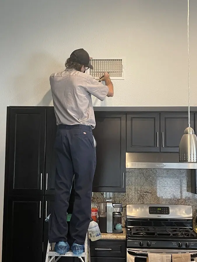 Technician inspecting an air vent during HVAC service in Destin